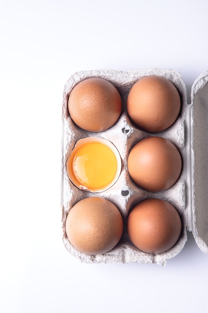 Vue de dessus des oeufs bruns sur carton d'oeufs isolé sur fond blanc.