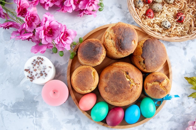 vue de dessus des oeufs de pâques colorés avec du pain de vacances et des gâteaux à l'intérieur du plateau sur une surface blanche