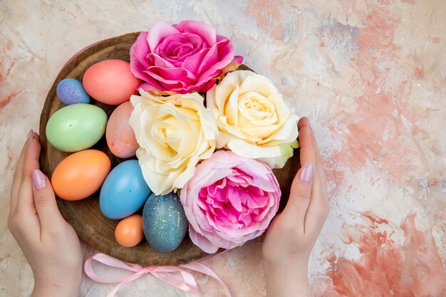 Vue de dessus des oeufs de pâques colorés avec des fleurs sur fond marron orné de vacances concept de printemps horizontal coloré