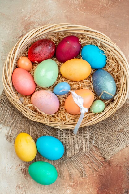 vue de dessus des oeufs de pâques colorés à l'intérieur du panier sur la surface claire