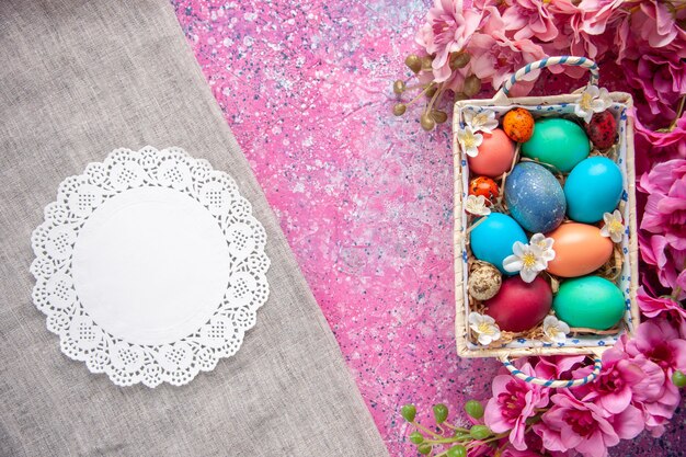 Vue de dessus des oeufs de pâques colorés à l'intérieur d'une jolie boîte sur une surface rose couleur de vacances printemps pâques concept coloré orné