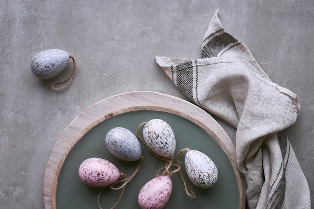 Vue de dessus des oeufs de Pâques décoratifs faits à la main dans des couleurs pastel sur un plateau en bois