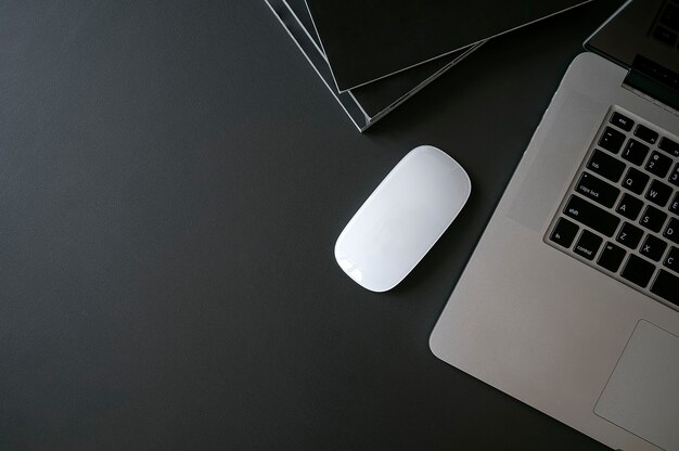 Vue de dessus de l'ordinateur portable avec souris et livres sur la table supérieure en cuir noir.