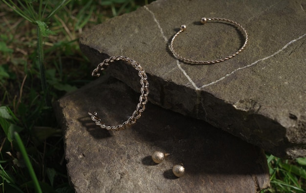 Vue de dessus de la paire de bracelets et boucles d'oreilles dorés brillants sur la pierre naturelle en plein air