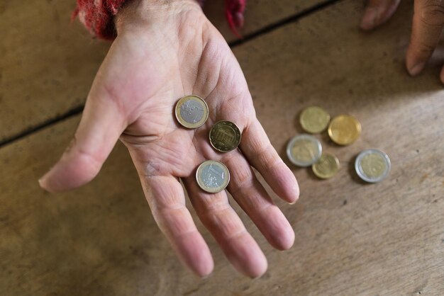 Vue de dessus d'un palmier senior masculin tenant des pièces en euros au-dessus d'un bureau en bois