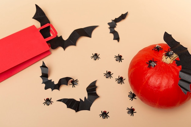 Vue de dessus sur un paquet rouge de fond beige avec des mouches, de la citrouille et des chauves-souris. Gros plan d'une fête d'halloween. mise en page d'invitation