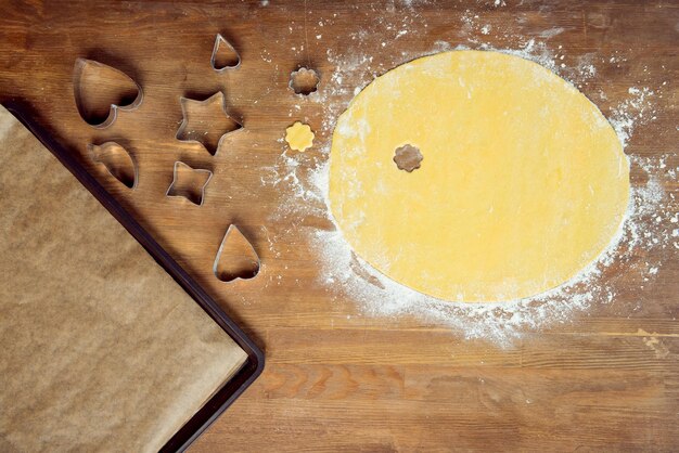 Vue de dessus de la pâte à biscuits en forme brute et des emporte-pièces sur une table en bois