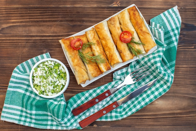 vue de dessus des pâtisseries vertes frites avec des verts et des tomates à l'intérieur de la plaque