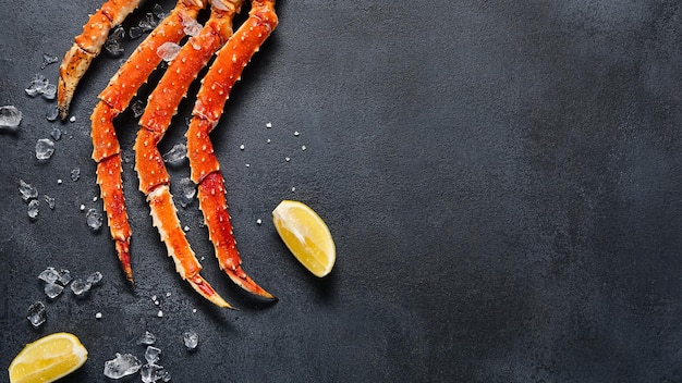 Vue de dessus des pattes de crabe sur fond sombre Fruits de mer de crabe de charcuterie sur table en ardoise noire Esthétique des fruits de mer crustacés Nourriture de viande de crabe de luxe à plat Fond de menu de fruits de mer avec pattes de crabe d'Alaska