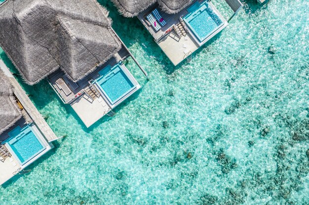 Vue de dessus, paysage aérien, villas de luxe sur l'eau de la station balnéaire tropicale, lagon marin. Belle plage de l'île