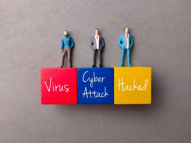 Vue de dessus personnes miniatures et bloc coloré avec texte Virus Cyber Attack Hacked sur fond gris