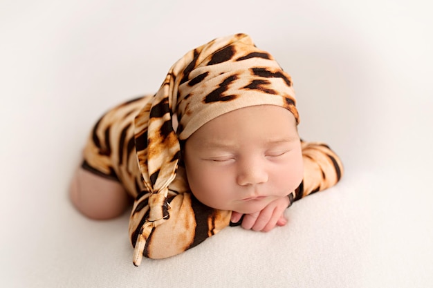 Vue de dessus d'une petite fille nouveau-née dormant dans une combinaison de tigre et un bonnet bringé sur la tête sur fond blanc Beau portrait d'une petite fille 7 jours sur 7 L'image d'un petit tigre