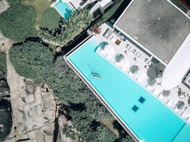 Vue de dessus photo aérienne d'un modèle sexy séduisant en maillot de bain beige se détendre dans la piscine de la villa de luxe