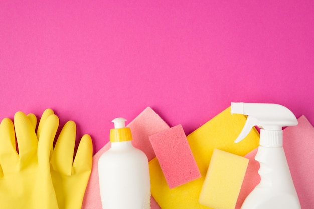 Vue de dessus photo de chiffons en viscose rose et jaune gants en caoutchouc éponges vaporisateur blanc et bouteilles de détergent en gel sur fond rose isolé avec espace vide