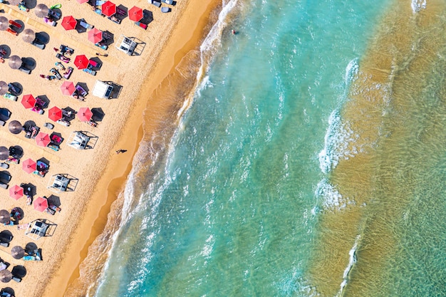 Vue de dessus photo de drone aérien de la plage de Banana avec de belles vagues de mer turquoise et des parapluies rouges Fond de voyage de vacances Mer Ionienne Île de Zakynthos Grèce