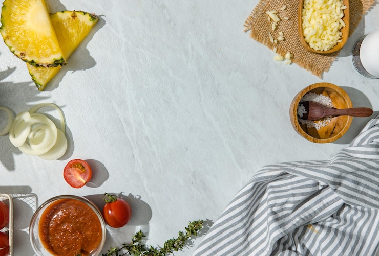 Photo vue de dessus photo d'espace publicitaire vierge sur une table vide autour avec des ingrédients alimentaires tranches d'ananas tomates et fromage à l'oignon dans une cuillère en bois sel dans un bol en bois ketchup et un chiffon propre