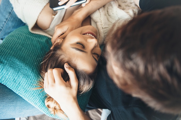 Vue de dessus photo d'une femme de race blanche aux cheveux bruns couchée sur les genoux de son amoureux avec un oreiller et lui sourire