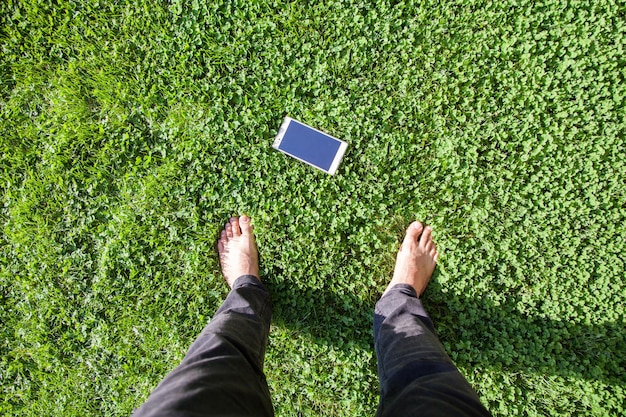 Vue de dessus des pieds humains et du téléphone portable sur la pelouse