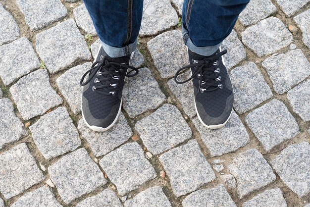 Vue de dessus des pieds sur les pavés en baskets