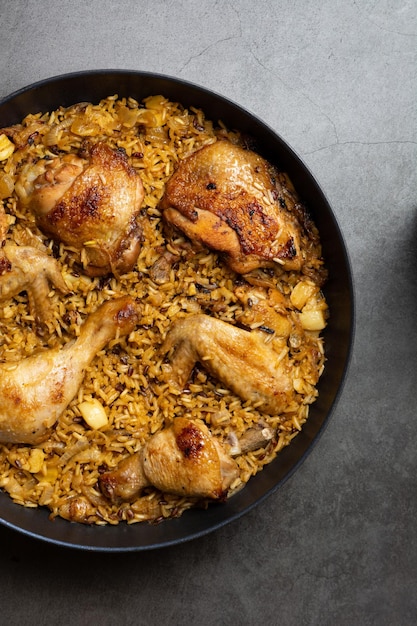 Vue de dessus pilaf Riz cuit au poulet frit avec zira à l'oignon et épices dans un chaudron sur fond de béton foncé