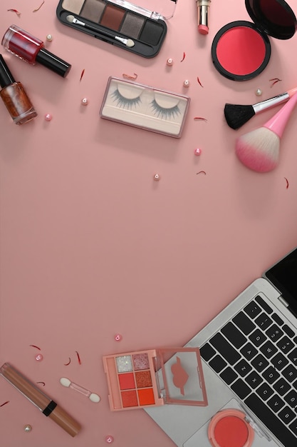 Vue de dessus des pinceaux de maquillage pour ordinateur portable et des cosmétiques sur fond rose Espace de travail féminin