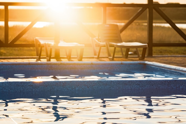 Vue de dessus de la piscine à l'eau claire en vacances sur fond de coucher de soleil