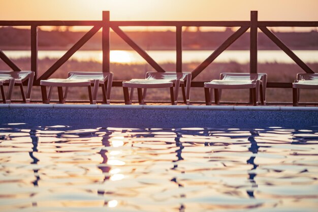 Vue de dessus de la piscine à l'eau claire en vacances sur fond de coucher de soleil