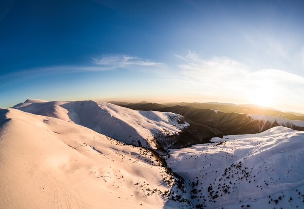 Vue de dessus d'une piste de ski inoubliable recouverte de neige située dans les montagnes du nord du pays par une froide soirée d'hiver ensoleillée. Concept de beauté de la nature nordique. Copyspace