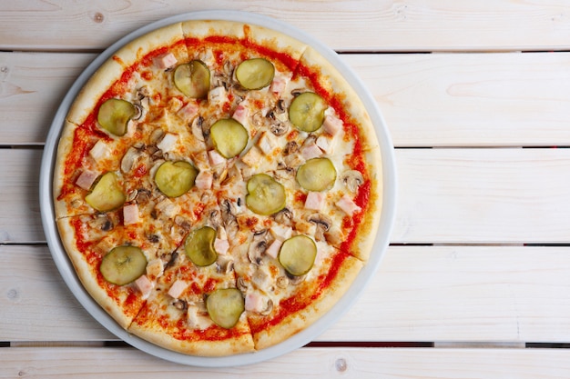 Vue de dessus de la pizza au jambon et concombre mariné