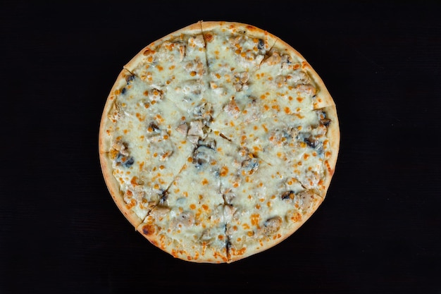 Vue de dessus de la pizza au poulet avec des morceaux de fromage et de maïs sur fond noir