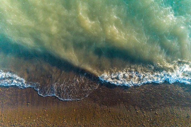 Vue de dessus d'une plage déserte. Photo aérienne par drone des vagues de l'océan atteignant le rivage.