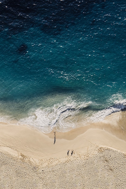 Photo vue de dessus de la plage de sable bleu et des gens marchant le long de la plage