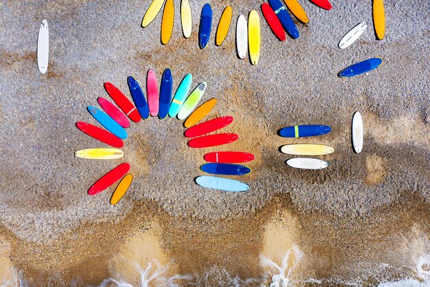 Vue de dessus des planches de surf colorées gisant de façon chaotique sur une plage de galets en France.
