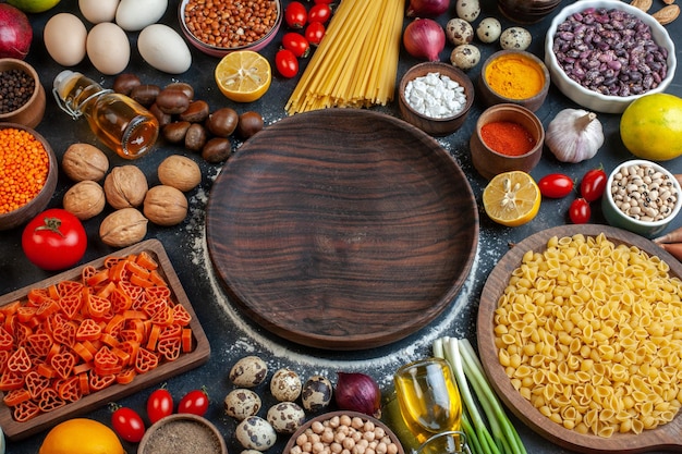 Vue de dessus plaque en bois marron autour de différents ingrédients sur fond sombre repas pâte alimentaire pâtes fruits couleur écrou