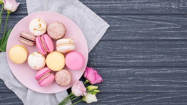 Vue de dessus de la plaque avec des macarons et des roses