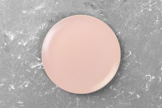 Vue de dessus de la plaque rose vide ronde mate sur l'espace de fond de ciment foncé pour votre conception