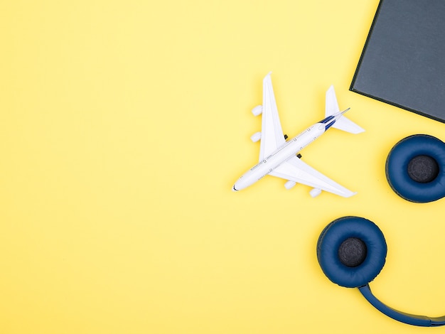 Vue de dessus à plat d'un avion sur fond jaune, avec des lunettes de soleil et un livre