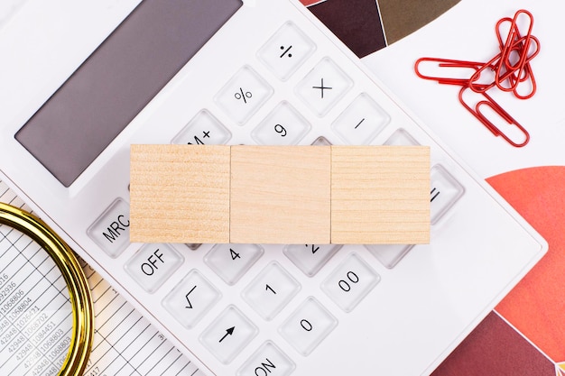 Vue de dessus à plat du bureau Espace de travail avec calculatrice blanche loupe trombones rouges et cubes en bois avec espace pour insérer du texte