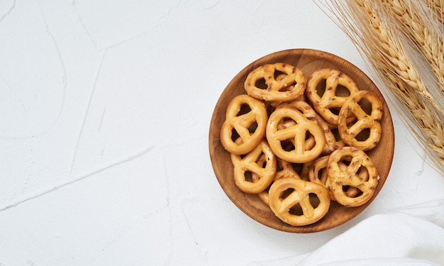 vue de dessus ou plat mini bretzel salé dans une assiette en bois sur fond de tableau blanc.