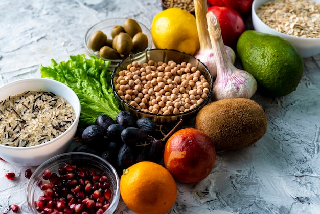 Vue de dessus à plat d'une sélection d'aliments sains avec des fruits, des légumes, des graines et des herbes vertes sur les tables