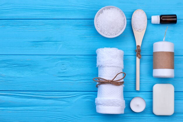 Photo vue de dessus à plat sur des trucs de spa de salle de bain sur bois bleu. serviette avec du savon à la bougie et du sel.