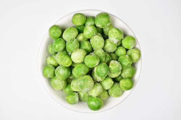 Vue de dessus des pois surgelés dans un bol isolé sur fond blanc avec un tracé de détourage