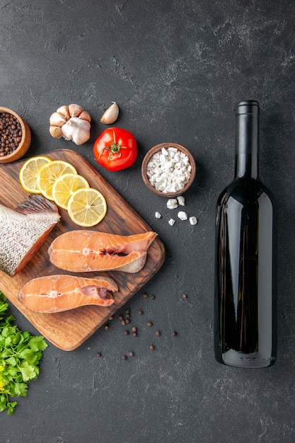 vue de dessus poisson frais avec citron bouteille de vin et légumes verts sur fond sombre poisson salade eau viande océan mer repas dîner fruits de mer