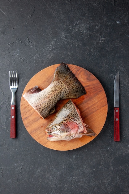 vue de dessus poisson frais tranché avec fourchette et couteau sur fond sombre repas de fruits de mer océan mer viande repas alimentaire salade poisson d'eau