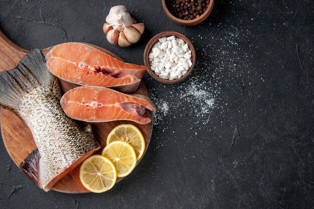 vue de dessus poisson frais avec des tranches de citron sur le fond sombre océan fruits de mer repas nourriture repas eau salade poisson de mer viande