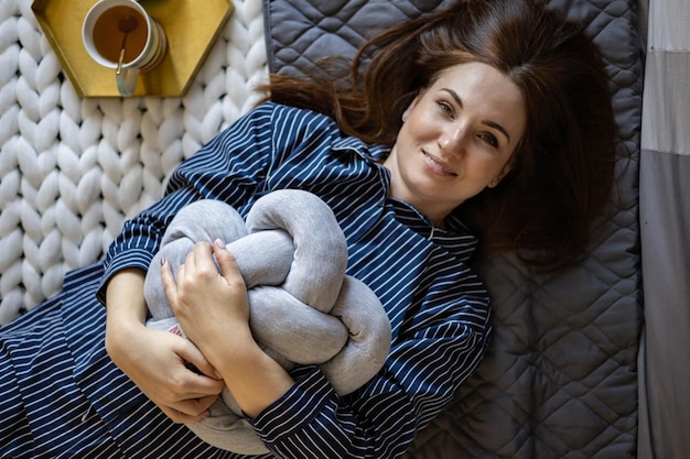 Vue de dessus portrait d'une femme domestique heureuse et détendue en pyjama allongé sur le lit avec du thé et du chocolat