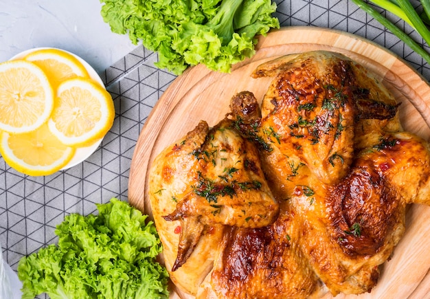 Photo vue de dessus poulet entier cuit au four sur une planche à découper avec des tranches de citron