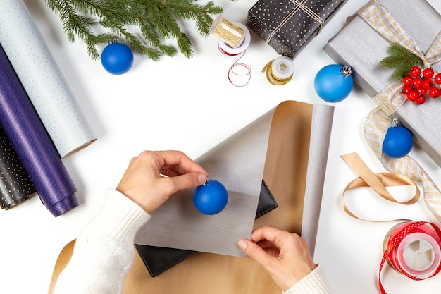 Vue de dessus pour femme mains emballage boîtes de cadeaux de Noël sur tableau blanc