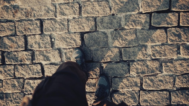 Photo vue de dessus pov d'un homme en chaussures marchant sur un ancien trottoir historique