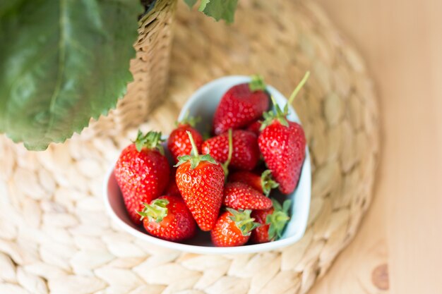 Vue de dessus de près de bol en forme de coeur de fraise fraîche sur la table. Espace libre. Copiez l'espace. Concept d'été.